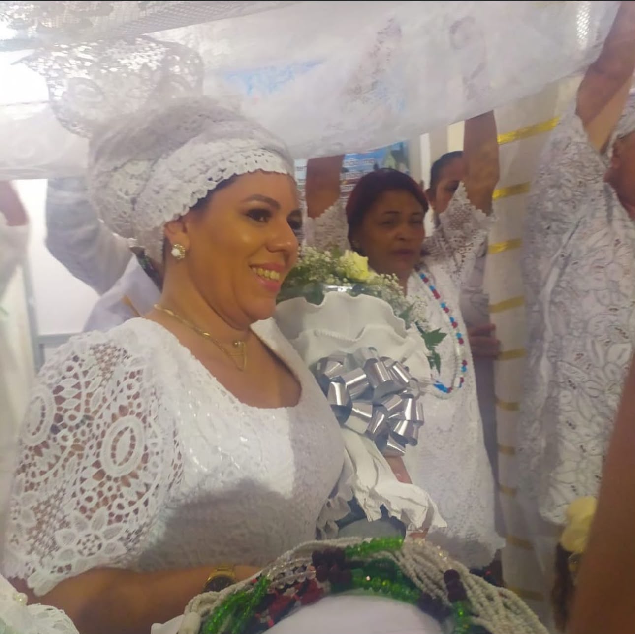 Mãe Débora vestida de branco, sorrindo durante sua consagração na Umbanda
